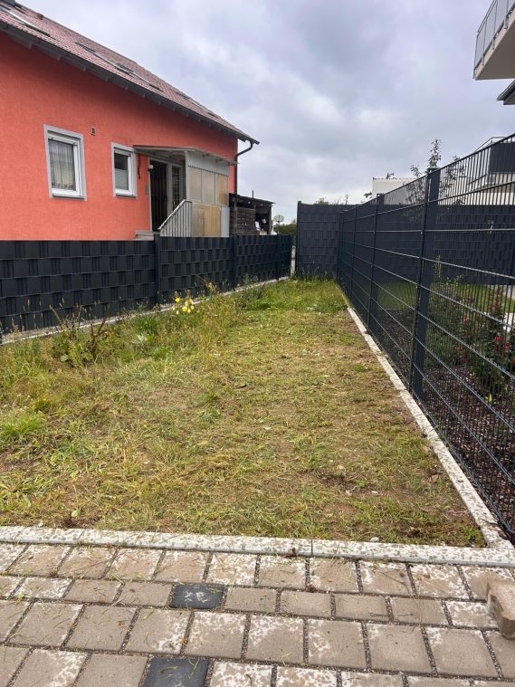 Rotes Haus und ein wildbewachsenem Grünstreifen