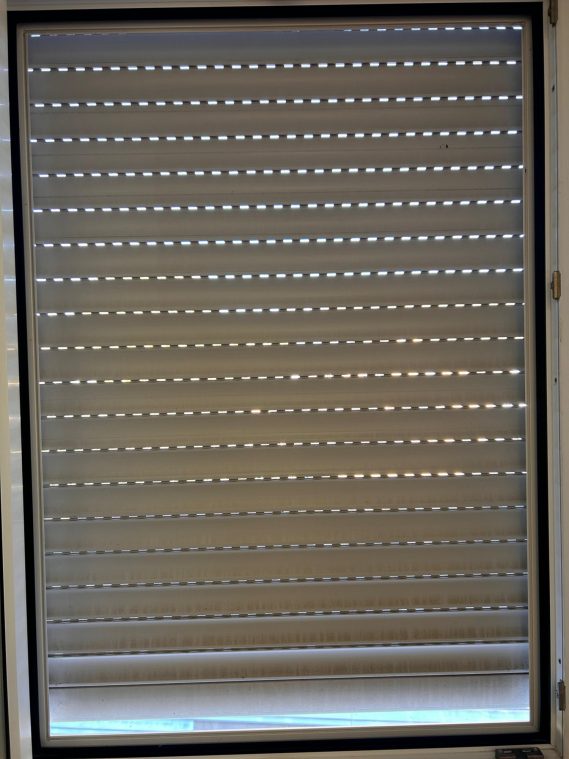 Fenster mit geschlossenem Rolladen und Verschmutzungen an den Lamellen