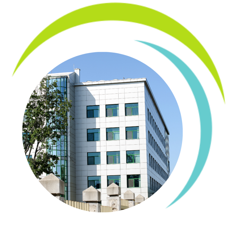 Modernes Gebäude mit Glasfront und Bäumen vor einem blauen Himmel.