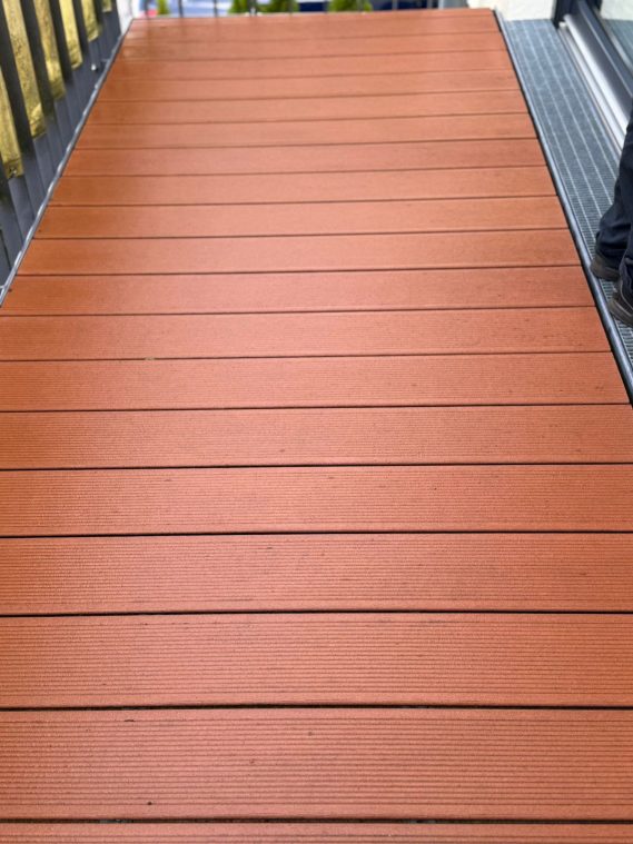 Holzartige Terrasse mit gleichmäßigen Dielen in warmen Brauntönen.